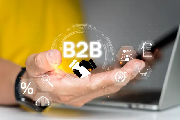 Person using a laptop with digital icons floating above, highlighting B2B, handshake, marketing, target, and growth. Concept of business-to-business strategy and technology.