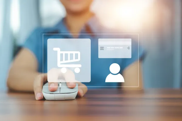 A person using a computer mouse with digital shopping icons projected in front. Icons include a shopping cart, credit card, and user profile, symbolizing e-commerce and online transactions.